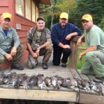 group of men showing off the grouse they got hunting