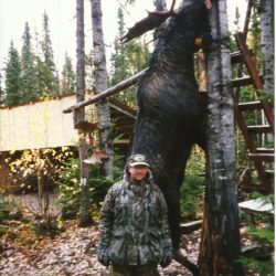 man standing by moose he hunted