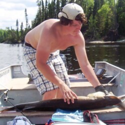 shirtless man with fish in boat