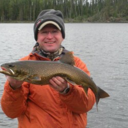 Man in orange jacket holding fish